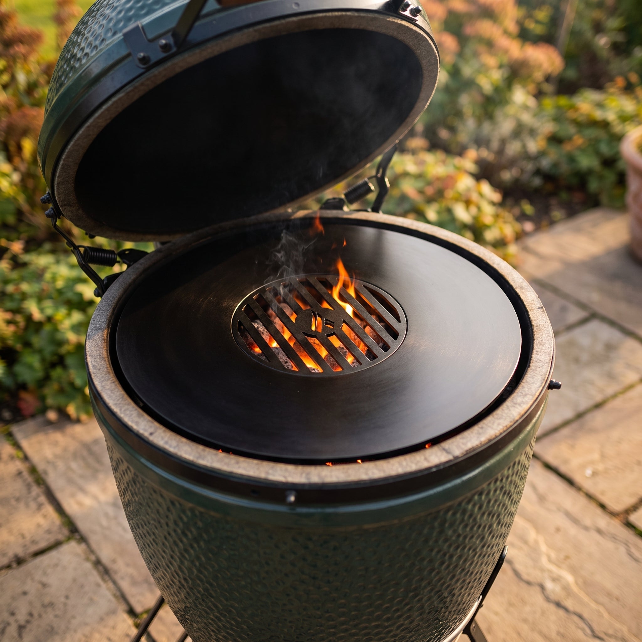 Arteflame Two-Piece Flat-Top Kit installed on a kamado grill, with lit charcoal glowing through the center grill grate